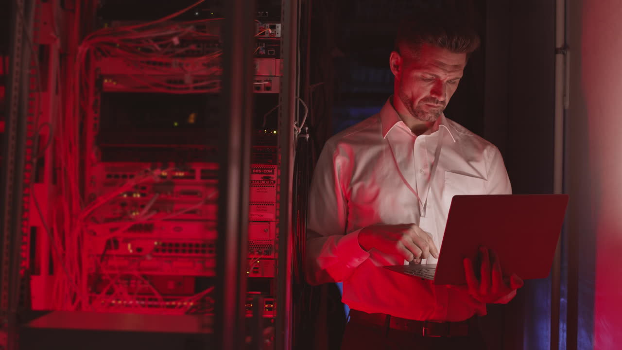 Man working on laptop in server room