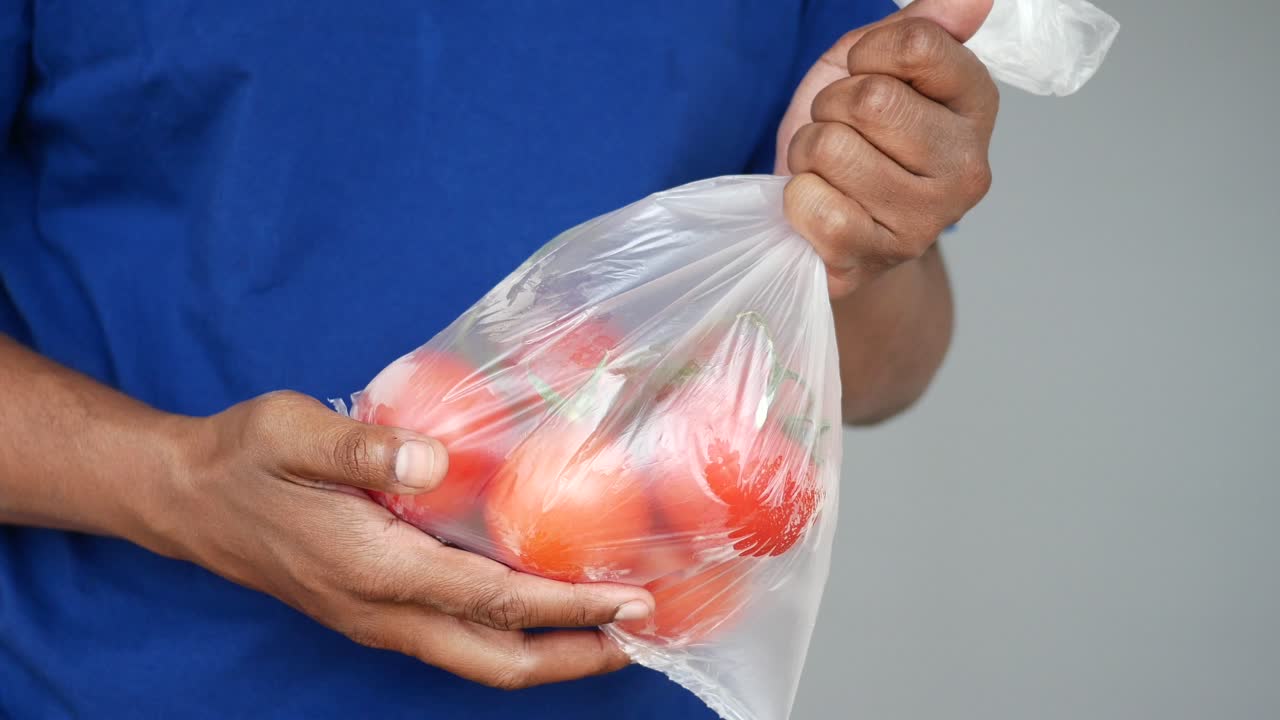 Persona con un sacchetto di plastica di pomodori