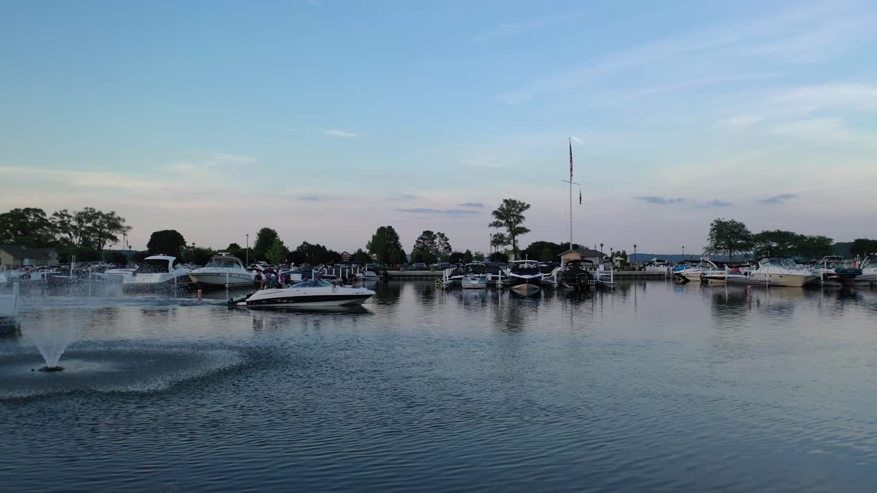 Barca che lascia il porto turistico per fare tubing con una bellissima fontana d'acqua inquadrata al Lago di Ginevra, Wisconsin