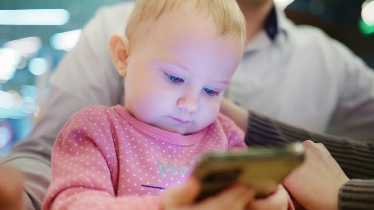 スマートフォンの画面を見つめる可愛い幼い女の子