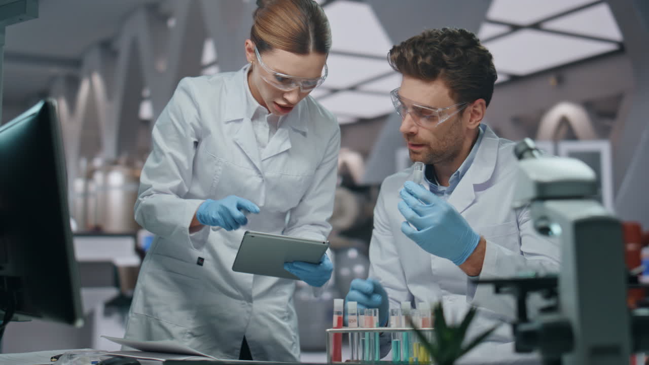 una mujer bioquímica discutiendo investigación médica con un colega en el laboratorio de cerca.