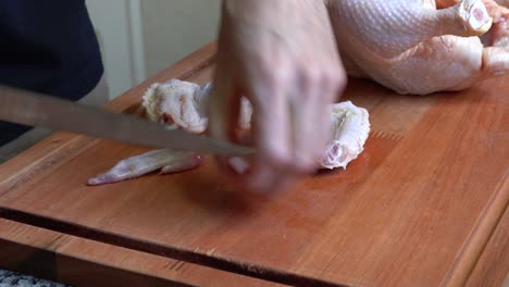 cropped view of a person cutting chicken wings at the kitchen