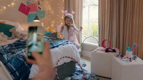 Fröhliches-Kleines-Mädchen,-Das-Sich-Im-Feenkostüm-Im-Schlafzimmer-Verkleidet,-Während-Die-Mutter-Mit-Dem-Smartphone-Ein-Foto-Macht-Und-Es-In-Sozialen-Medien-Teilt