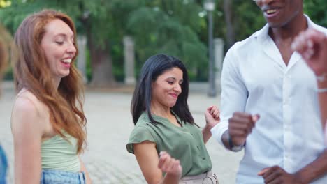 a diverse group of young friends dancing happily outdoors in a park