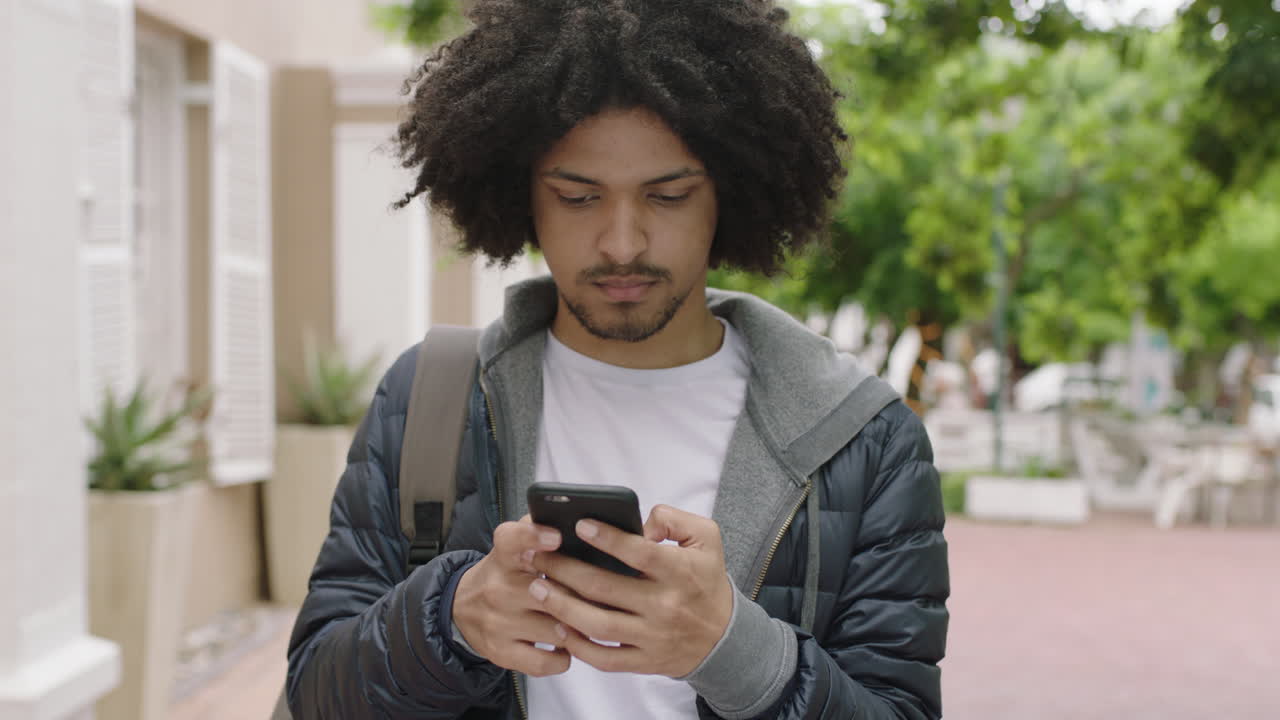 ritratto di un giovane studente di razza mista che invia messaggi di testo, naviga online utilizzando smartphone, social media sullo sfondo di una città urbana