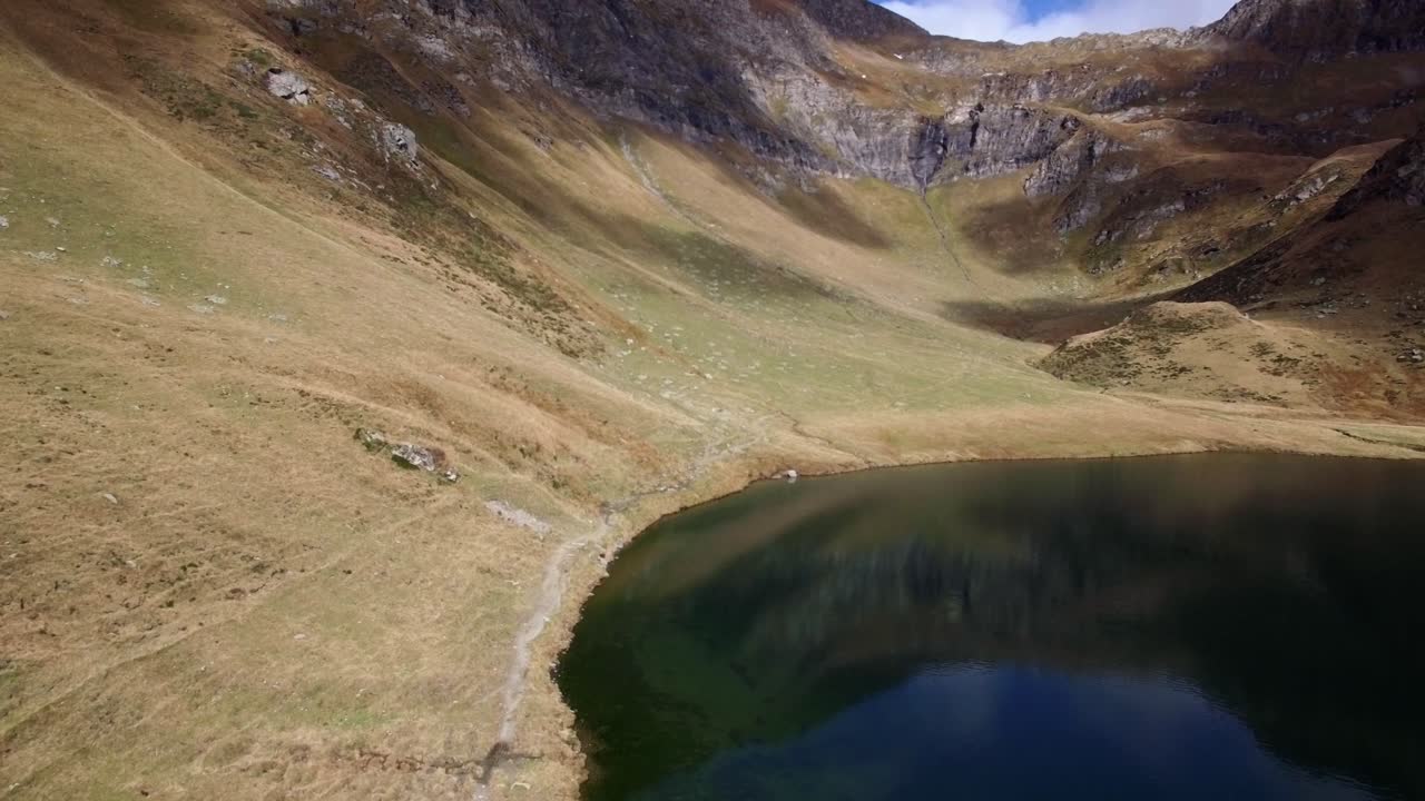 Luftfoto af reflekterende dybblå bjergsø med massivt bjerg i baggrunden om efteråret i Schweiz