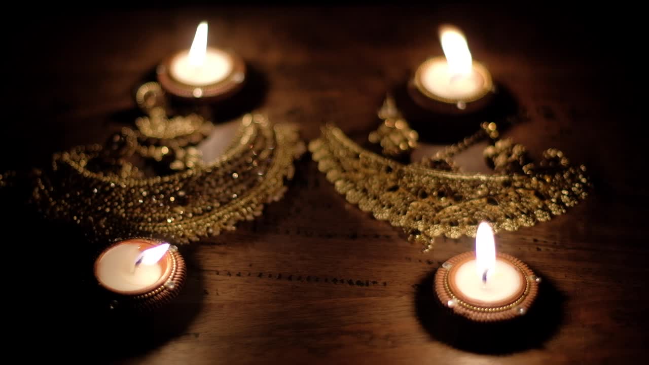 Close-up defocusing out-of-focus bokeh of rich and luxurious South east Asian Hindu golden wedding jewelry lit beautifully with light from diya candles,  for blessing and worshipping.