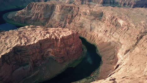 horseshoe bend meander, cinematic aerial view of colorado river sandstone canyon, arizona usa