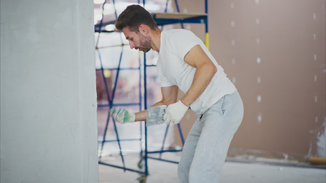 Man Focused on Refinishing Wall Surface with Trowel and Proper Techniques in Modern Interior Space During Home Improvement or Renovation Project