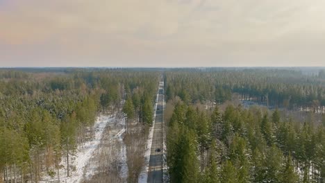 Sanfter-Flug-Hinter-Einem-Auto-über-Einen-Winterlichen-Wald-Aus-Einer-Höheren-Luftposition,-Konzept-Für-Eine-Reise