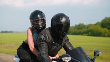 woman with beloved boyfriend biker rides past green field