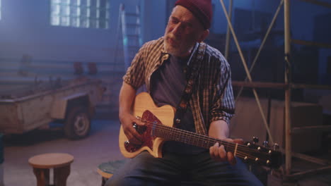 senior man playing guitar in a workshop