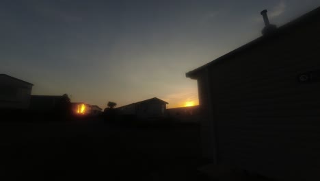 Glowing-sunset-timelapse-disappearing-behind-Welsh-holiday-park-silhouetted-static-caravan