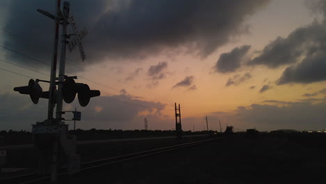 drone shot passing low by silhouetted railroad crossing sign in texas, u.s.a.