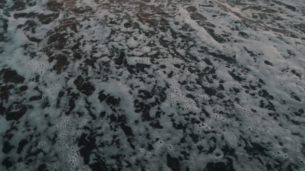 Onde sulla spiaggia di sabbia nera di El Paredon in Guatemala al tramonto