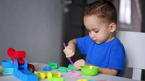interested baby boy is cutting the plasticine with a stick. sculpturing as a hobby for kid.