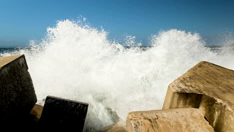 incessant waves crash into dolosse protecting the harbour wall