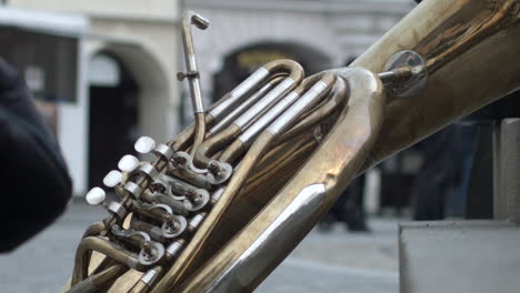 a giant brass instrument lies against stair on the street as a child steps past in melnik, czech republic