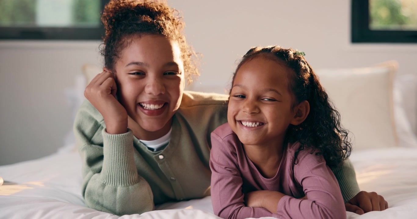 Two Happy Sisters Lying on Bed Together