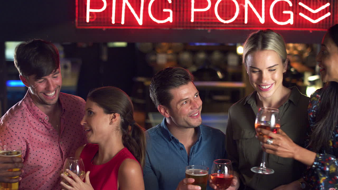 한 무리의 친구들이 술을 마시고 밤에 술집에서 건배를 하고 있습니다.