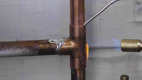 welding the top and bottom of a copper pipe tee fitting during a burst pipe diy home repair