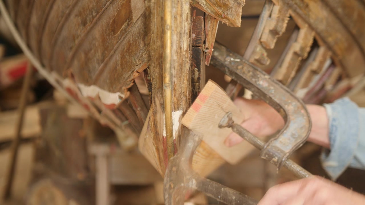 Inchiodatura di una tavola dello scafo in posizione per la riparazione di una barca in legno.