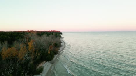 rotating reveal of panoramic waterfront coast with dense trees changing colors in wisconsin