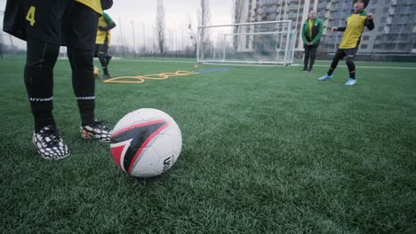 a children's football team trains at the stadium under the guidance of a coach. kids in sports uniforms practice ball exercises, improve technique, and develop teamwork on the green field