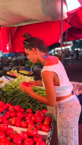 woman shopping for tomatoes at a farmer's market