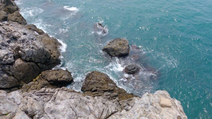 Onde blu dell'oceano che si infrangono contro una scogliera rocciosa a Busan, Corea del Sud.