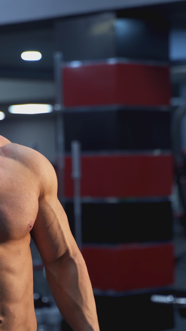 Handsome bodybuilding man have a rest after training. Young shirtless man training hard on the gym. Vertical video