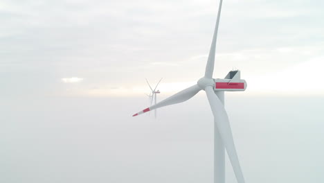 aerial shot of windmill turbines above a layer of dense mist, producing green, clean energy cropped