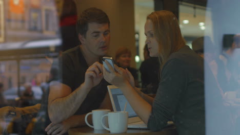 Jóvenes-Usando-Teléfonos-Inteligentes-Y-Hablando-En-Un-Café.