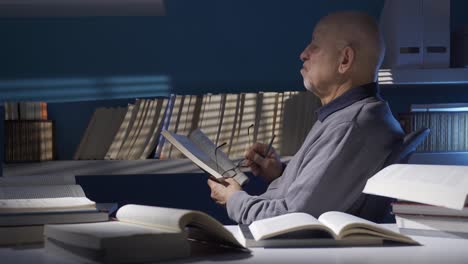 old man reading a book in the dark room.