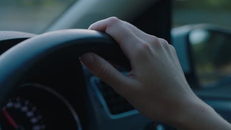 woman driver hands on steering wheel driving car in city on the road at rush hour travelling to destination at sunset