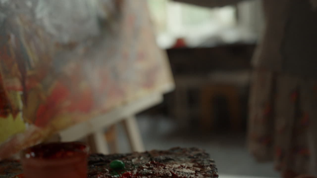 알려지지 않은 화가의 손이 실내에서  ⁇ 솔을  ⁇ 고 있습니다. 스튜디오에서 그림을 그리는 사람들.