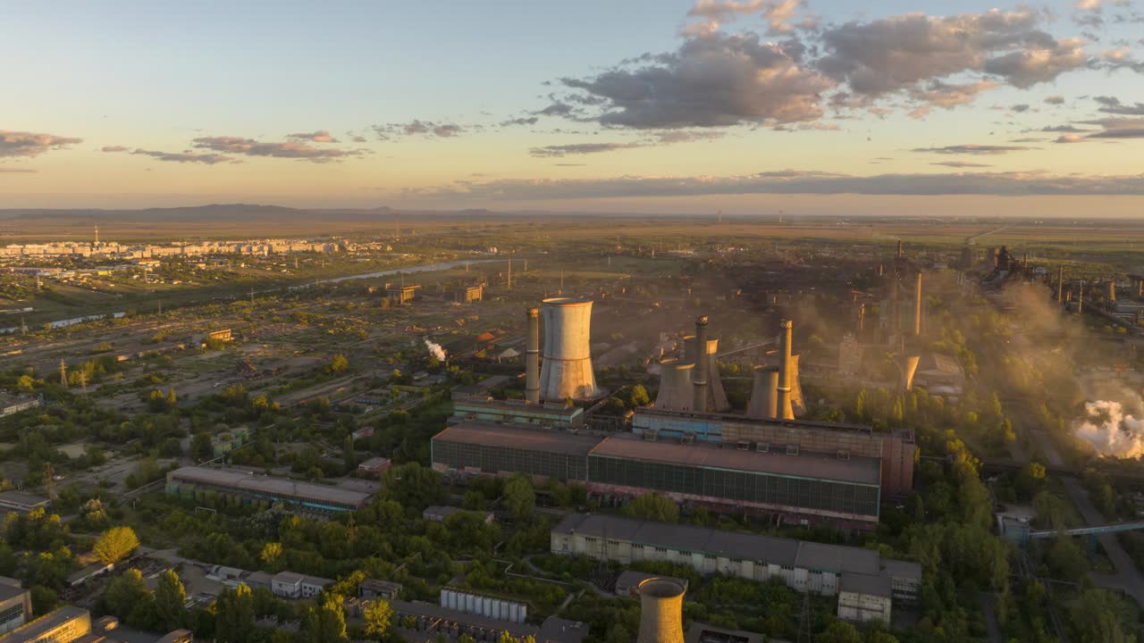 hiperlapso aéreo circular que enfoca una fábrica de reciclaje de metales que emite vapores al atardecer