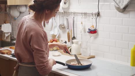 mujer freyendo hongos y cebollas en sartén en la estufa