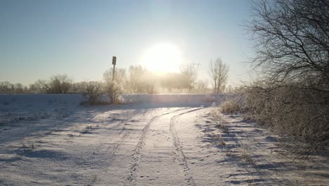 snowy farm field next to railway in poland with bright sun in blue sky background