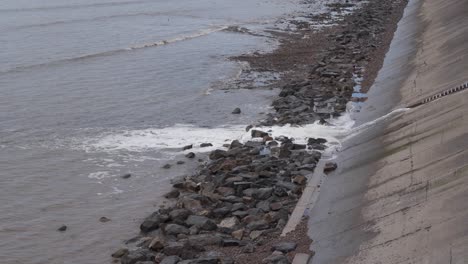 Water-being-released-from-the-artificial-beach-in-Weston-super-Mare-into-the-sea,-waves-crushing-into-the-rocky-beach