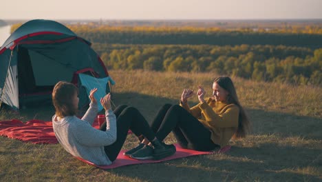 girls tourists do abs exercises on mat at campsite