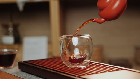 pouring tea into a glass cup during a traditional chinese tea ceremony