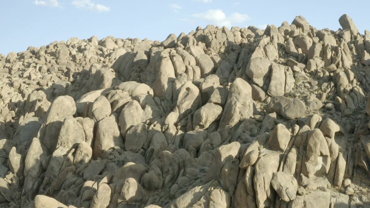 Volo sopra le gigantesche formazioni rocciose delle Alabama Hills in California con la città di Lone Pine sullo sfondo.