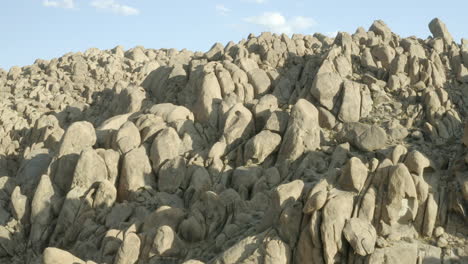 vuelo sobre las formaciones rocosas gigantes de las colinas de alabama en california con la ciudad de lone pine al fondo