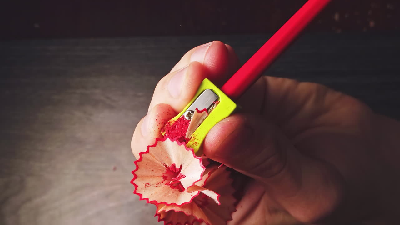 Overhead slow motion of sharpening the pencil in sharpeners on top of the wooden table