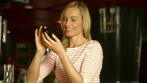 woman using her phone at the bar