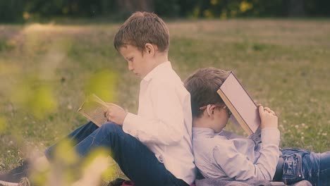 Erschöpfte-Schüler-Sitzen-Auf-Dem-Grünen-Rasen-Im-Garten-Und-Lesen-Bücher