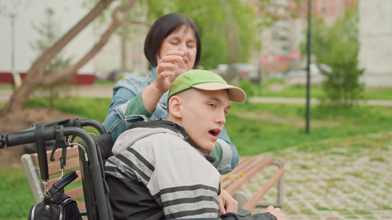 Playful Woman With Teen Friend, Laughter And Friendship Between Woman And Teen In Wheel Chair, Casual Park Scene Showcasing Playful Woman And Young Teen Sharing Lighthearted Connection