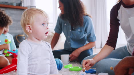 amigos con niños pequeños jugando en el suelo en la sala de estar