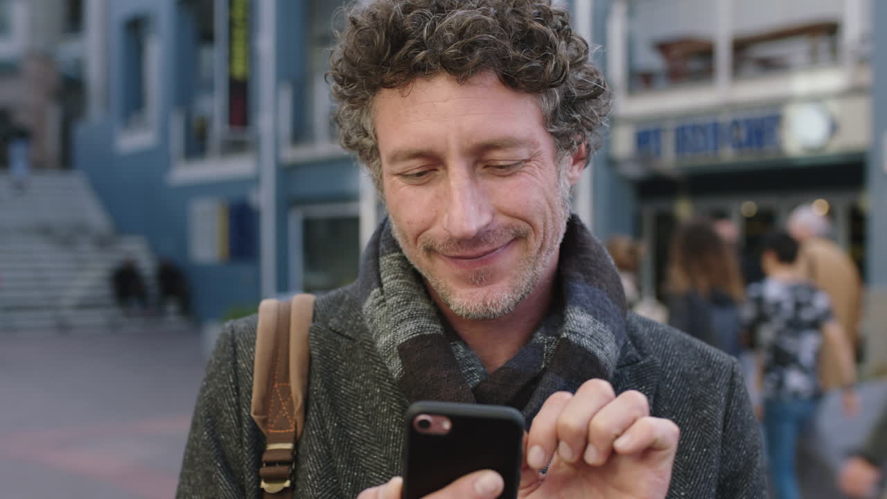 ritratto in slow motion di un uomo caucasico attraente e maturo che sorride navigando utilizzando l'app di messaggistica per smartphone godendo della tecnologia mobile